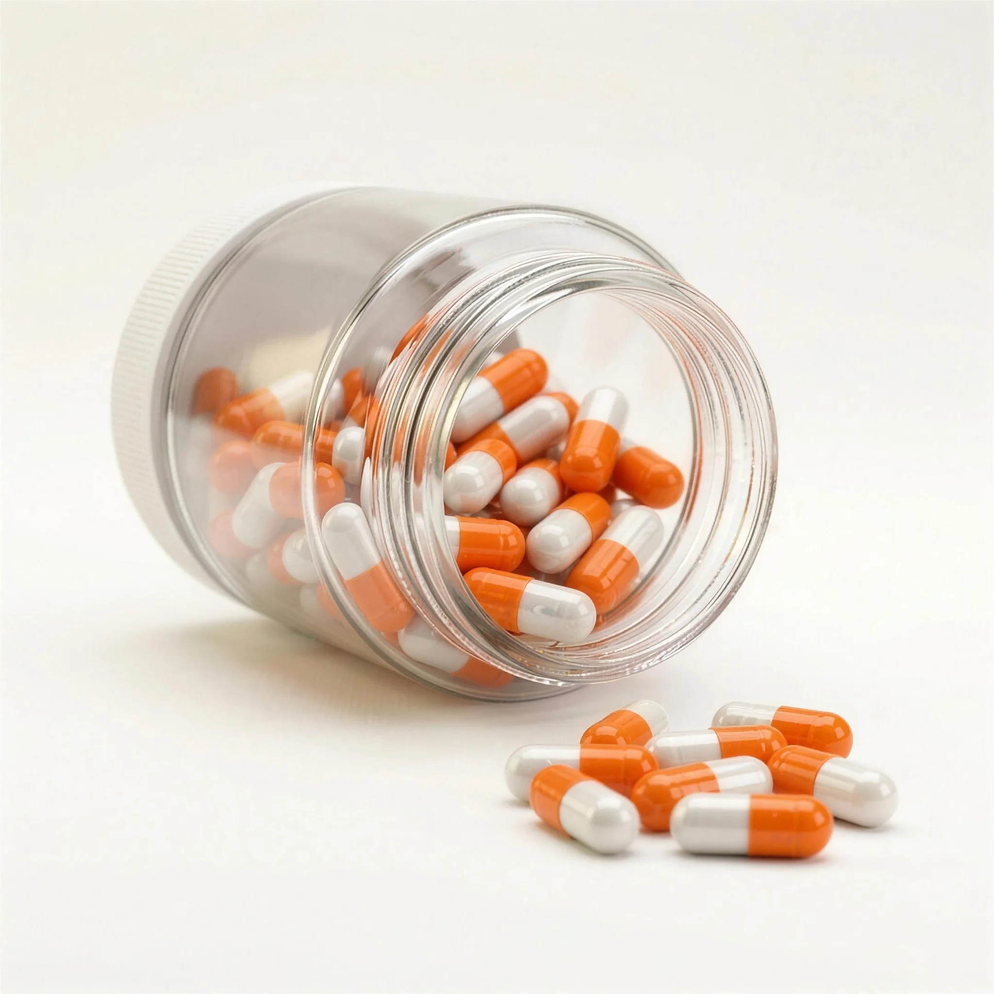 A glass jar tipped on its side, spilling orange and white capsules.